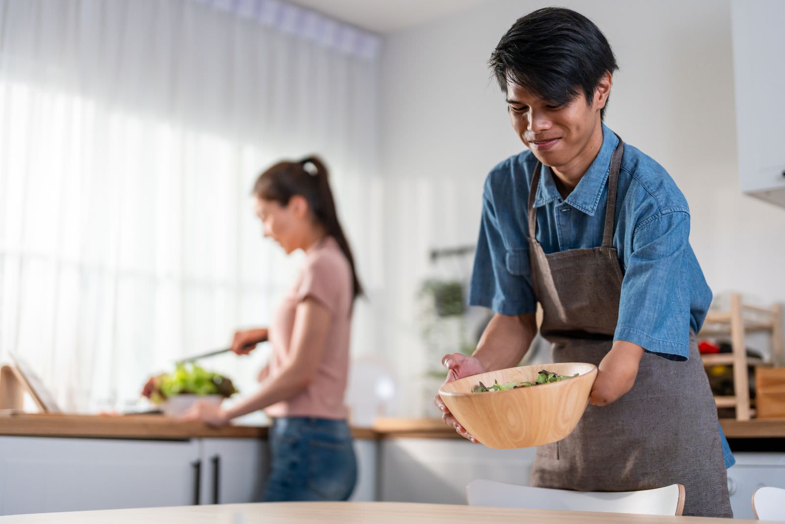 a man missing the lower half of his left arm carrying a bowl of salad to a table