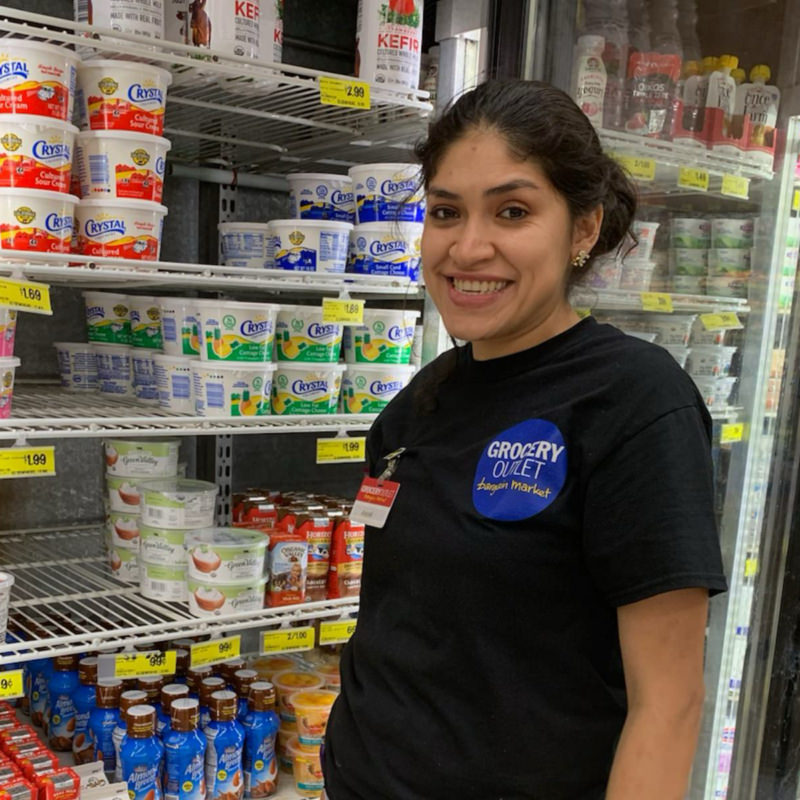 a woman smiling while working in a grocery store