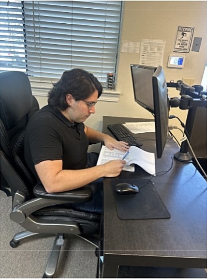Andrew reviewing documents at a desk while working for Bright Ideas through Customized Employment Services in Merced