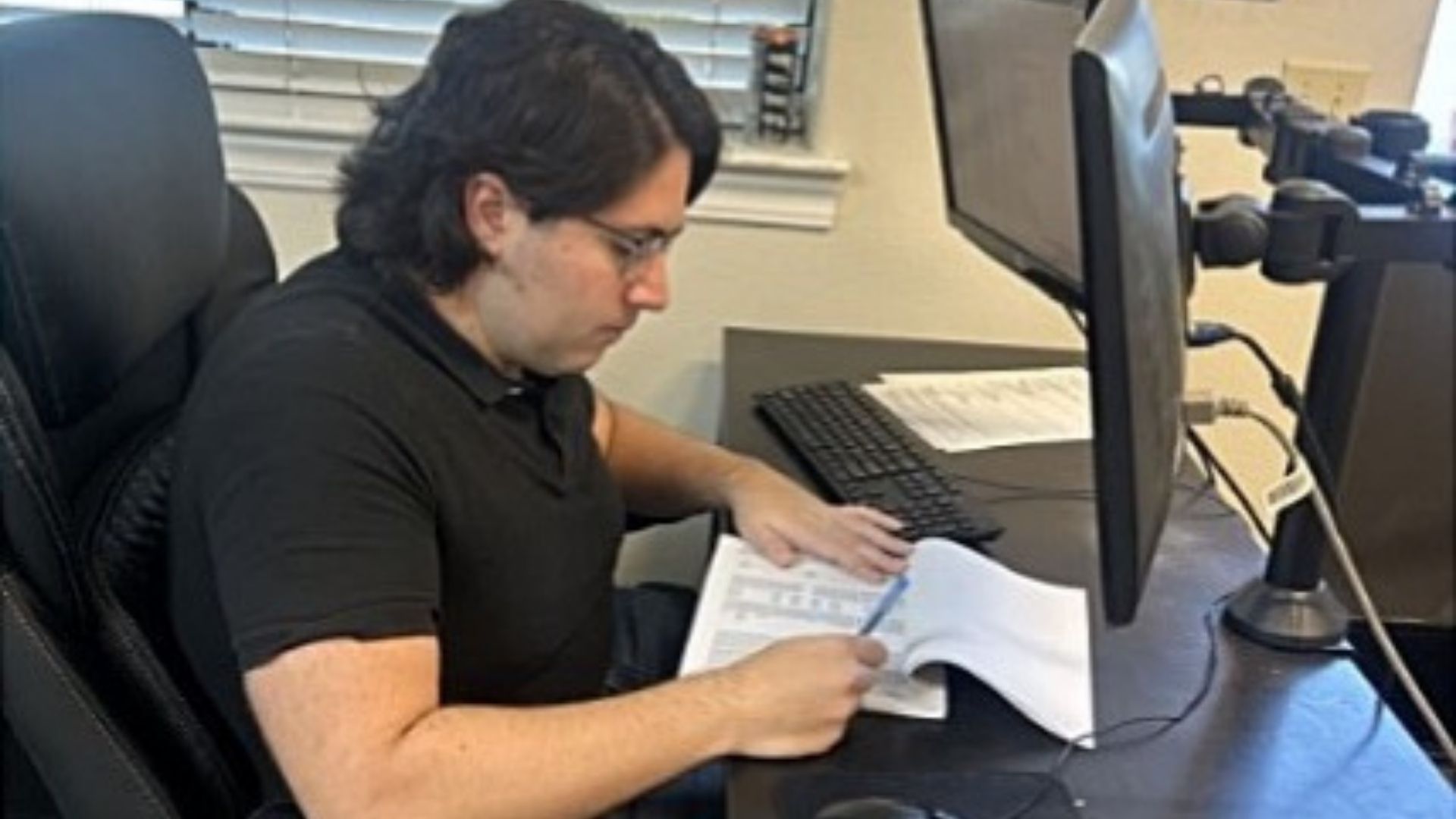 Andrew reviewing documents at a desk while working for Bright Ideas through Customized Employment Services in Merced