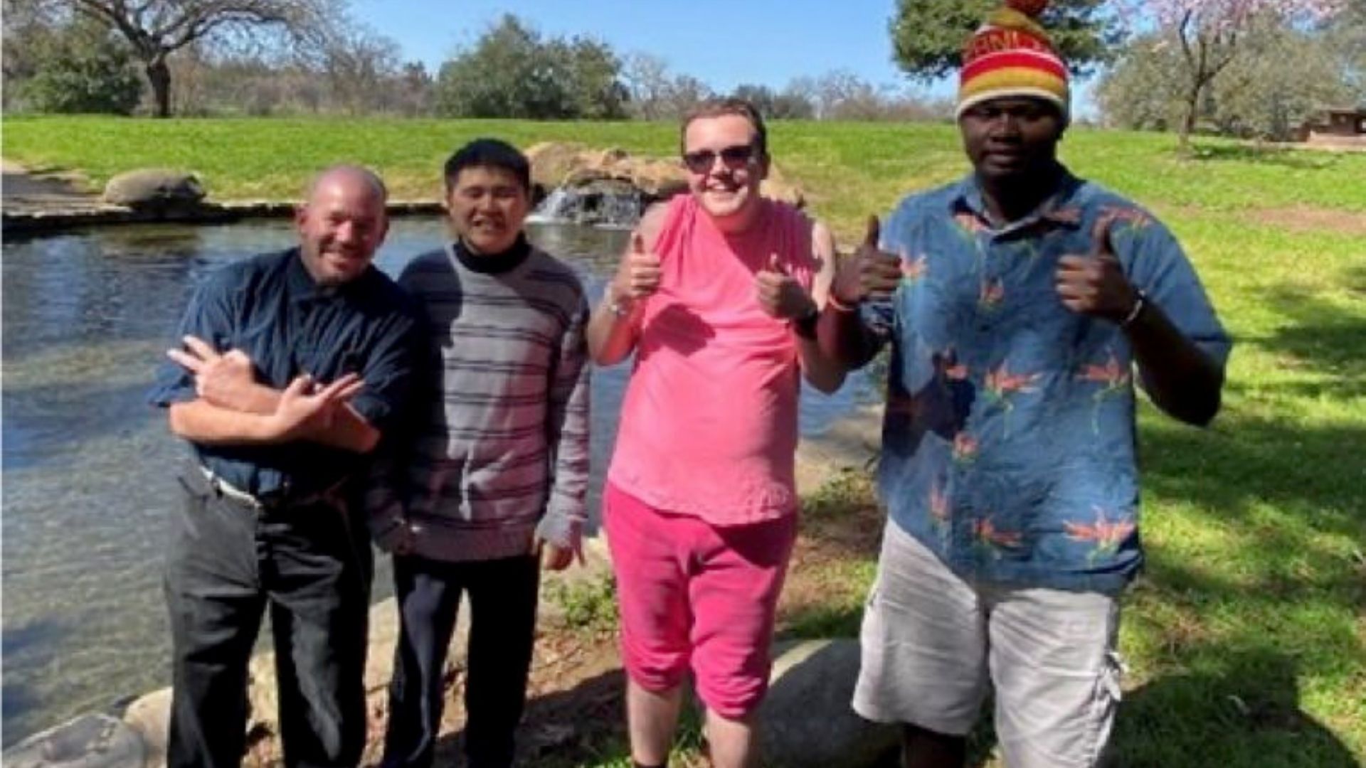 Matthew S., David V., Henry B., Kenneth T. standing in front of a lake giving a thumbs up pose.