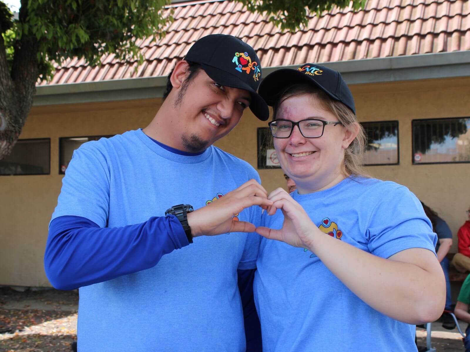 Two CV Training Center consumers smiling and making a heart shape with their hands during a life skills and social development activity in Stockton, CA