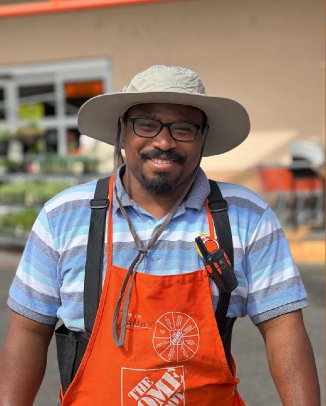 A Home Depot employee standing in his uniform in front of a local store. 