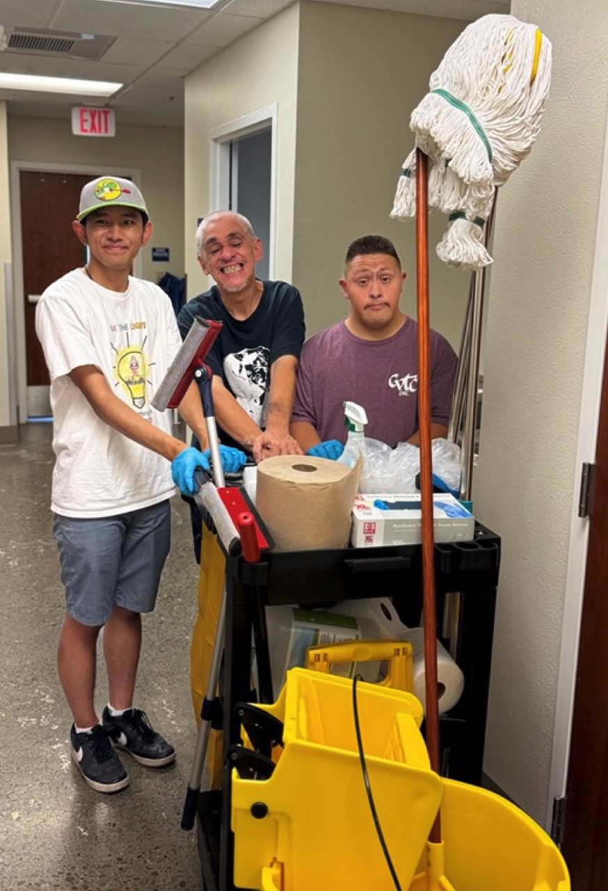 Nathan P., Manuel R., Francisco D. pushing a janitorial cart.
