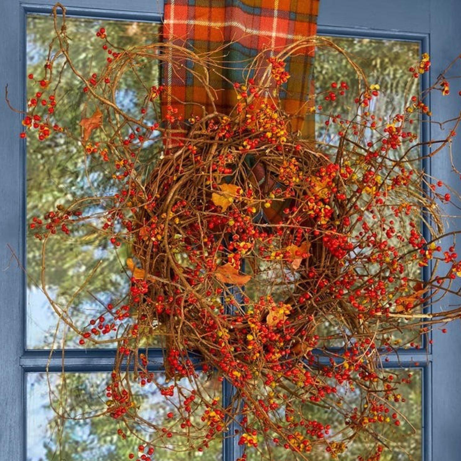 A fall wreath hanging on a blue door.