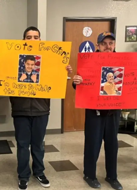 Chris and Francisco standing, holding political posters.