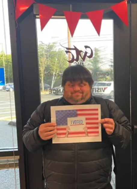 Connor standing a sign that says I Voted.