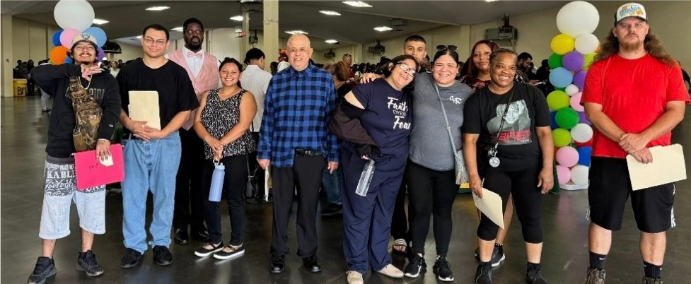 Fresno West participants and staff standing together at the Fresno Fair Job Fair, several holding folders.