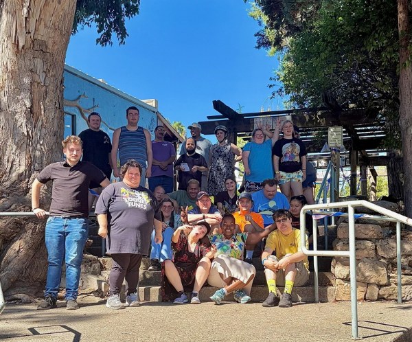 Jackson and Valley Springs participants and staff gathered on outdoor steps under a large tree for the August birthday celebration.